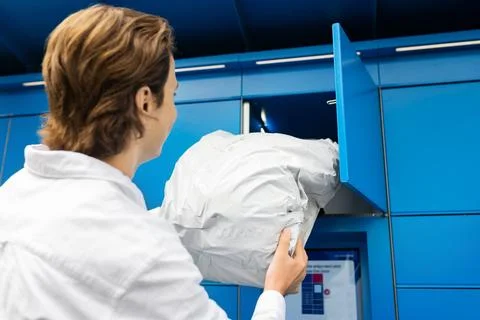 Man picking up a package from a blue parcel locker. Contactless delivery, e.. Stock Photos