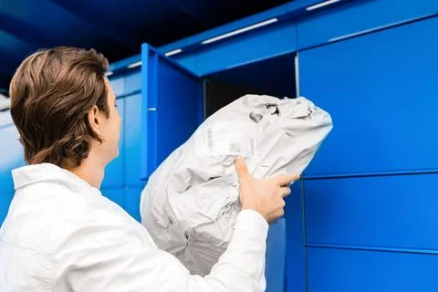 Man picking up a package from a blue parcel locker. Contactless delivery se.. Stockfoto's
