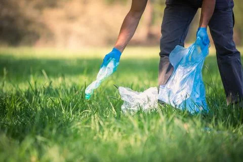 Man picking up plastic bottle, garbage collecting in forest cleaning planet 库存照片