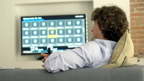 Man picking programme on tv while sitting and relaxing on the sofa Stock Footage 72138198
