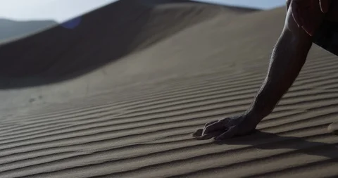 Man picking up sand on an untouched dune in a desert Stock Footage 107609671