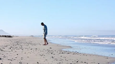 A man picking up shells on the beach Stock Footage 333717500