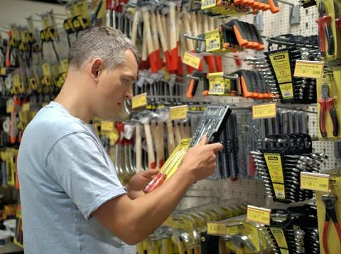 Man picking a tool from a hardware store wall Stock Photos