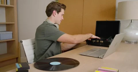 Man picking vinyl placing record on player taking call typing on laptop with Stock Footage 347725805