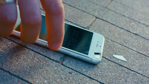 A man picks up a broken smartphone from the road. Stock Footage 166921678