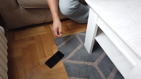 A man picks up a cellphone from the floor with a broken screen Stock Footage 124805270