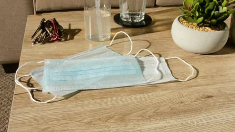 Man Picks COVID-19 Face Mask From Table Prior to Leaving Home Video stock 138159396