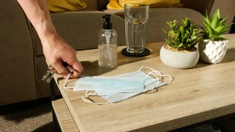Man Picks COVID-19 Face Mask From Table Prior to Leaving Home Video stock 138159577