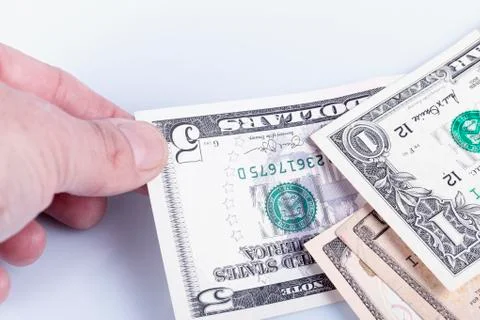 A man picks up a five dollar bill from between a pile and isolated on white Stock Photos
