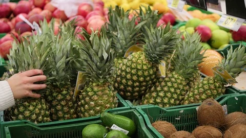 Man picks fruit pineapple in the supermarket Vidéo 70163484