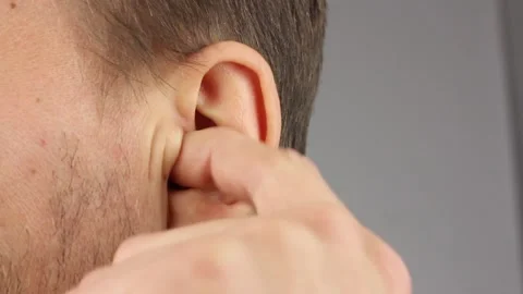 Man picks his left ear with his index finger, loud noise or itch, close-up Видео 145535814