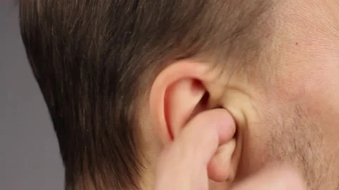 Man picks his right ear with his index finger, loud noise or itch, close-up Видео 145535815