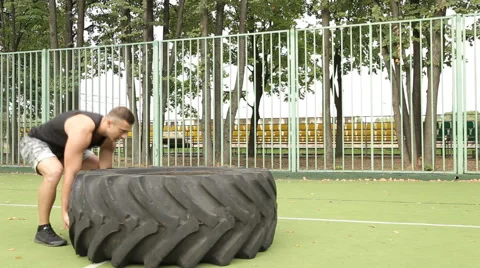 A man picks up a large tire on the Playground. Stock Footage 66429879