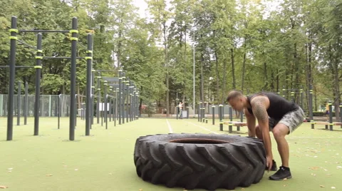 A man picks up a large tire on the Playground. Vidéo 66430158
