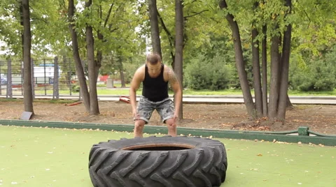 A man picks up a large tire on the Playground. Vidéo 66430877