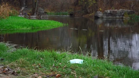 A man picks up a mask thrown by the river. cleanliness and order concept Stock Footage 156628757