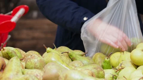 A man picks up pears in a bag at the store. Stock Footage 228633248
