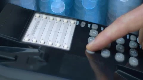 A man picks up the phone, dials 911 on a push-button wired black telephone Stock Footage 259680142