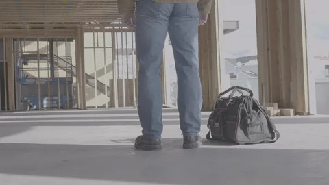 Man picks up tool bag and walks through a construction site. Stock Footage 102124877