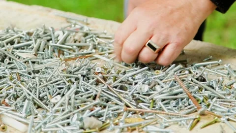 Man Picks Valid Screws from a Pile of Screws Stock Footage 257973074