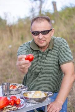 A man on a picnic on a summer day eats baked vegetables Stock Photos