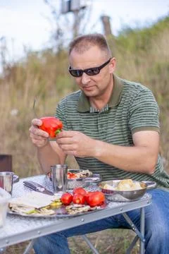 A man on a picnic on a summer day eats baked vegetables Photos