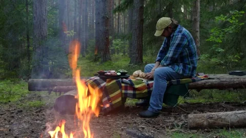 A man on a picnic in the woods in the fall makes sandwiches and warms himself by Stock Footage 283670582