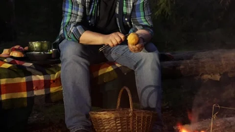 A man on a picnic in the woods in the fall makes sandwiches and warms himself by Vídeos de archivo 283671537