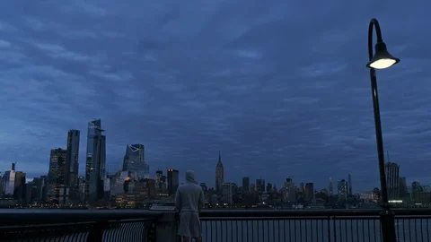 Man at pier looking Panoramic view of Manhattan Skyline at Dusk 4K Stock Footage 106596724