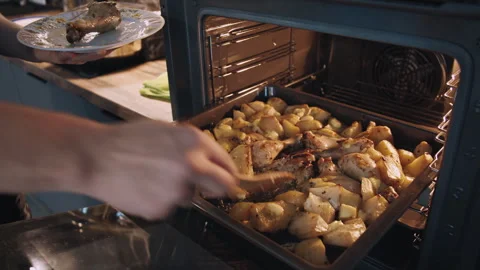Man piles extra servings on plate, oven-cooked meal of chicken legs and potatoes Stock Footage 310658780
