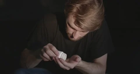 Man with pills sitting on the floor Stock Footage 168458215