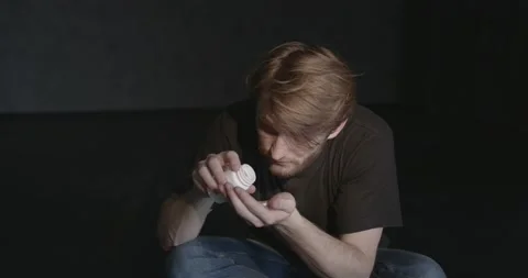 Man with pills sitting on the floor Stock Footage 168458228