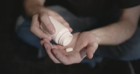 Man with pills sitting on the floor Stock Footage 168458234