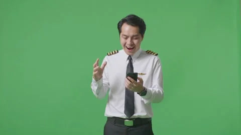 Man Pilot Looking At Smartphone, Smiling, And Saying Wow Standing Green Screen Stock Footage 244394130