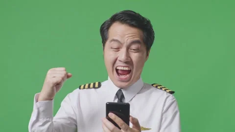 Man Pilot Looking At Smartphone Then Screaming Goal Celebrating On Green Screen Stock Footage 244396913