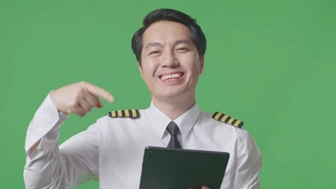 Man Pilot Smiling And Pointing To Tablet In His Hand While Standing Green Screen Stock Footage 244398472