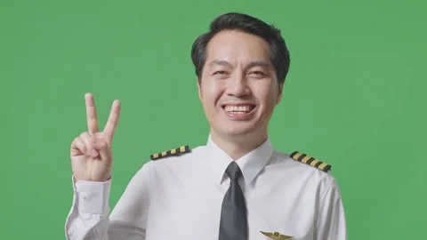 Man Pilot Smiling And Showing Peace Gesture To Camera  Standing ON Green Screen Stock Footage 244395984
