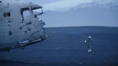 Man in pilot suit getting closer a wrecked plane on an Iceland beach Vidéo 104239746