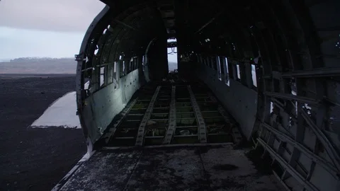 Man in pilot suit getting inside a wrecked plane on an Iceland beach Stock Footage 104240652