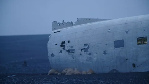 Man in pilot suit getting out  a wrecked plane on an Iceland beach Video stock 104239927