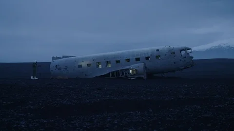 Man in pilot suit getting in a wrecked plane on an Iceland beach Stock Footage 104239584