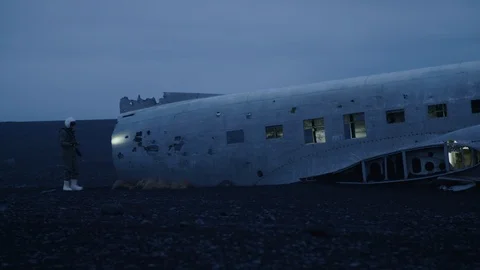 Man in pilot suit getting in a wrecked plane on an Iceland beach Stock Footage 104239712