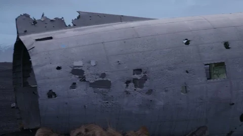 Man in pilot suit getting in a wrecked plane on an Iceland beach Stock Footage 104240076