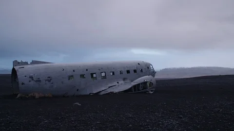 Man in pilot suit walking around a wrecked plane on an Iceland beach Stock Footage 104240088