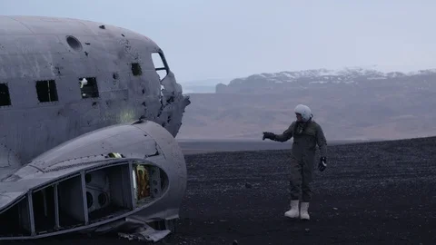 Man in pilot suit walking around a wrecked plane on an Iceland beach Video stock 104240102
