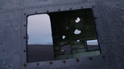 Man in pilot suit walking inside a wrecked plane on an Iceland beach Stock Footage 104240101