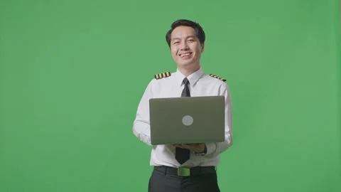Man Pilot Using A Laptop And Smiling To Camera While Standing On Green Screen Stock Footage 244394852