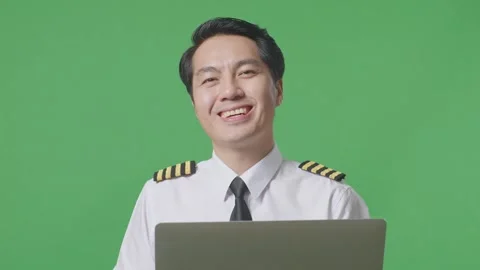 Man Pilot Using A Laptop And Smiling To Camera While Standing On Green Screen Stock Footage 244398158