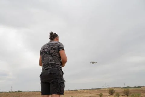 Man piloting drone flying over countryside landscape 스톡 사진