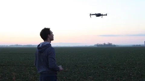 Man piloting drone at sunset field Stock Footage 98100065